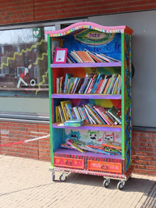 912598 Afbeelding van een kleurrijke minibibliotheek met kinderboeken bij de ingang van de Brede School Dichterswijk ...